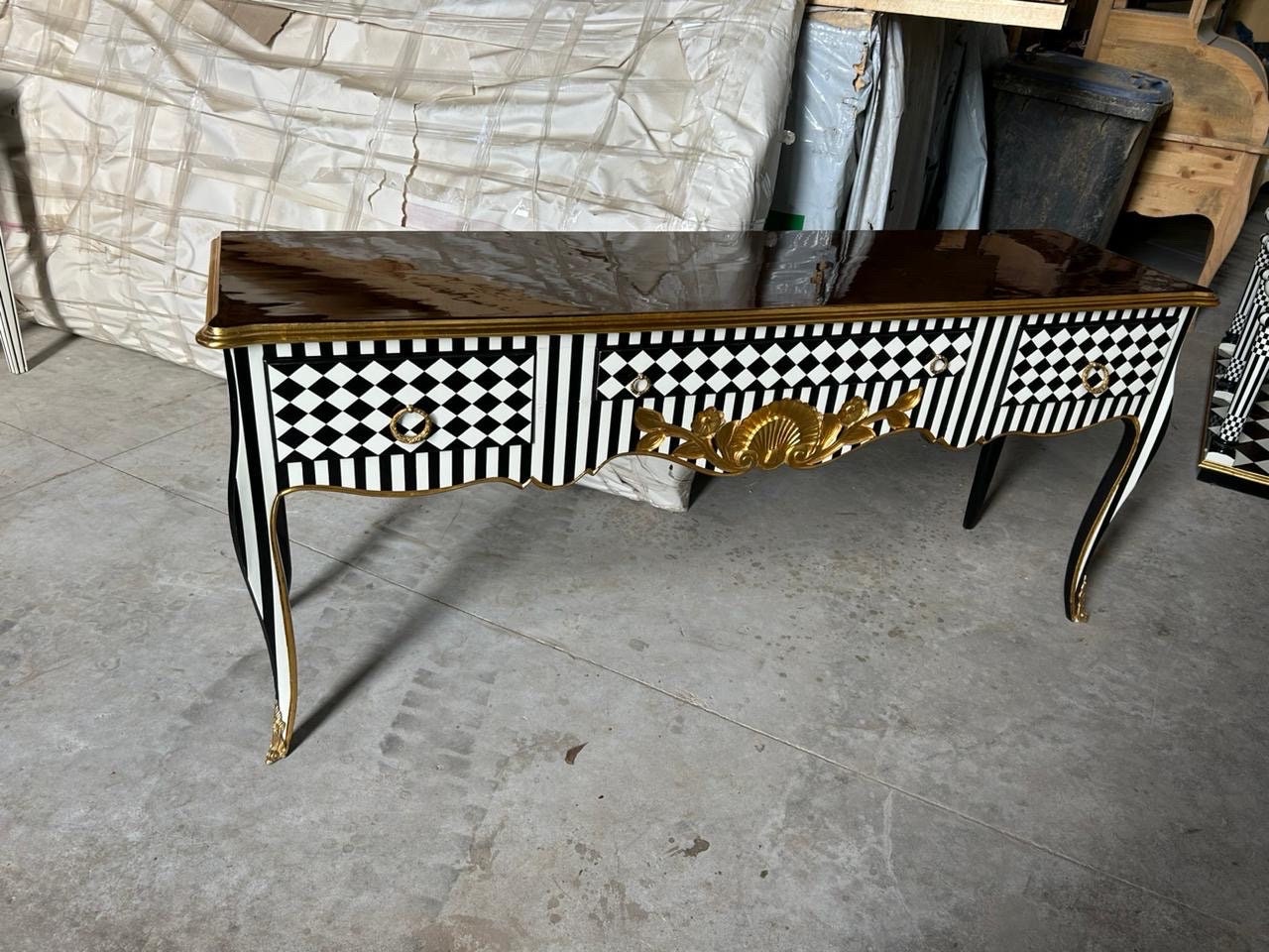 May include: A black and white console table with gold accents and a black and white checkered pattern. The table has two drawers and a glossy top.