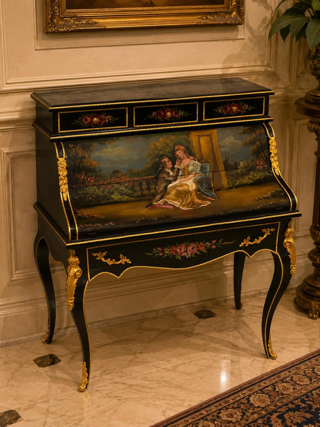 May include: A black roll-top desk featuring gold-toned metal accents on the legs and frame. The front panel displays a painted scene of two figures in a garden setting. Three small drawers at the top are decorated with floral motifs and gold knobs.