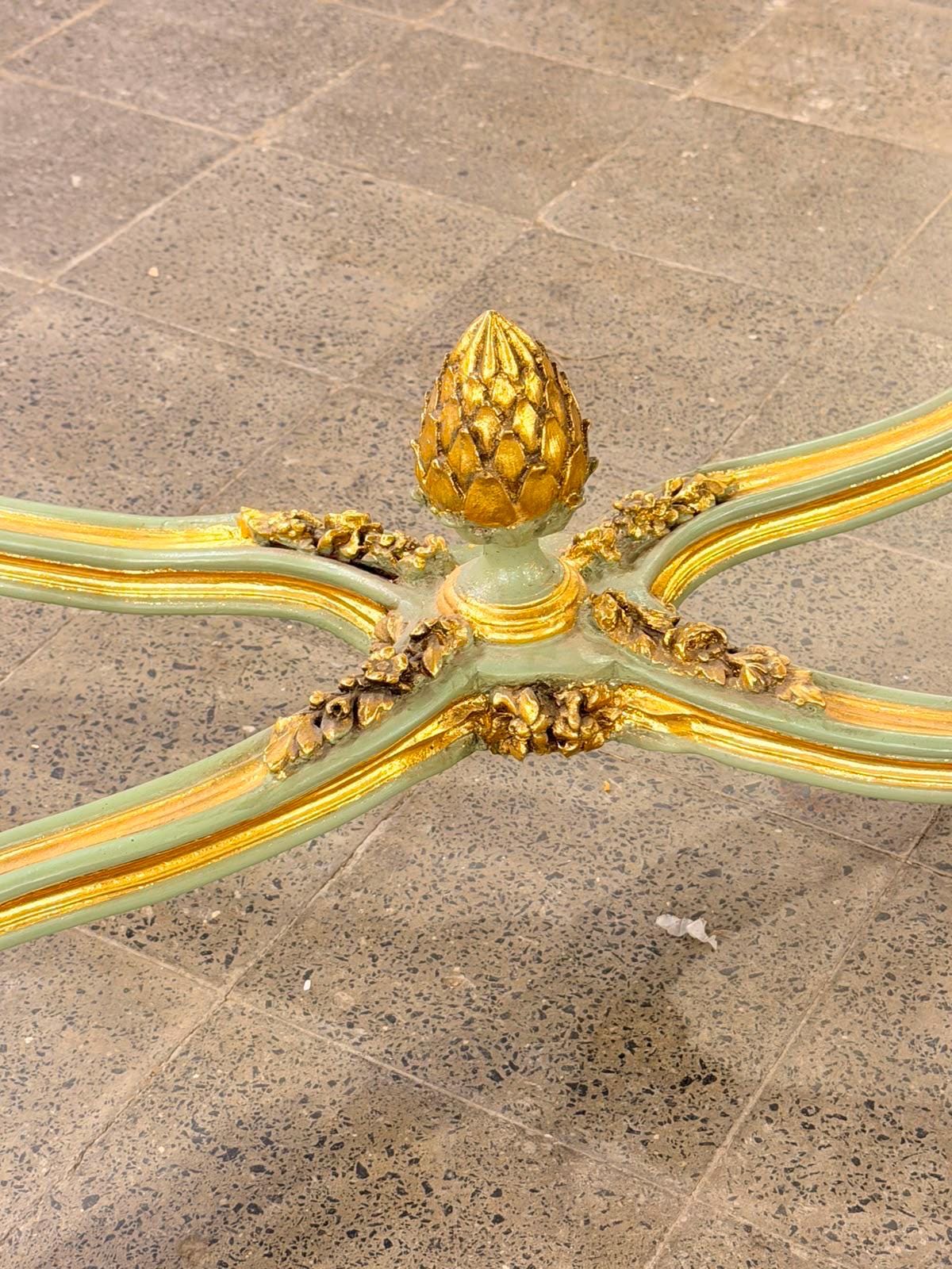 May include: A light green and gold painted table base featuring an X-shaped frame with curved legs. The center junction is adorned with a prominent gold-colored finial shaped like a pinecone, surrounded by intricate gold floral carvings.